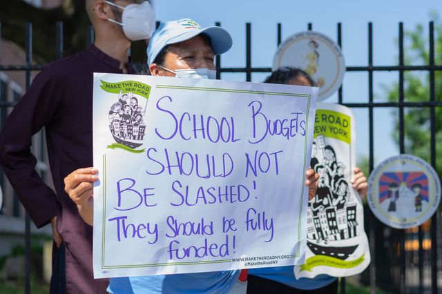 A protestor at a public school in Queens voices opposition to New York City's plan to reduce school funding for next school year.
